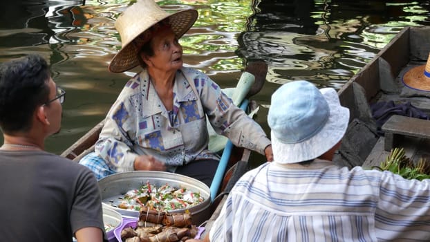 BANGKOK, THAILAND, 13 JULY 2019 Lat Mayom floating market. Traditional classic khlong river canal, local women in long-tail boats with oriental thai cusine assortment. Iconic asian street food selling