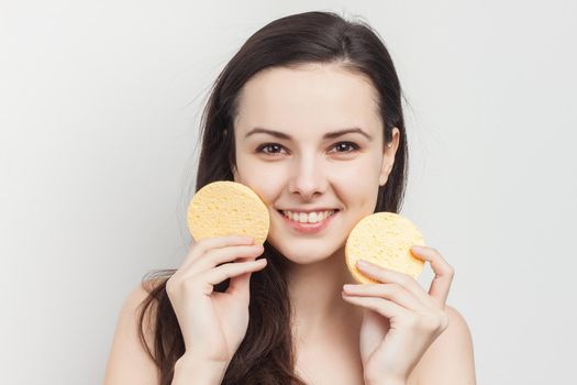 brunette with loose hair holding sponges clean skin
