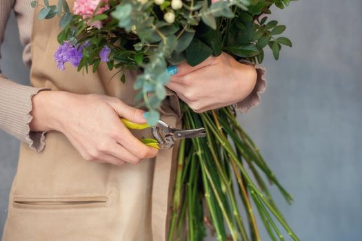 Florist at work. Florist cuts the stems of flowers in a bouquet with a secateurs