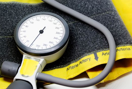 a portable sphygmomanometer resting on a yellow cuff for adults with a velcro closure.