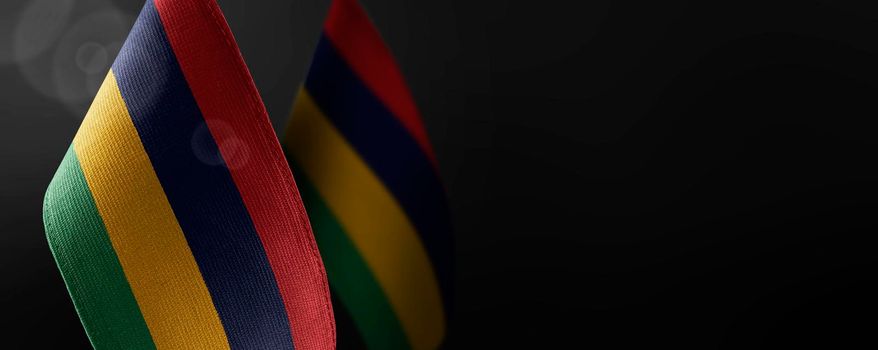 Small national flags of the Mauritius on a dark background