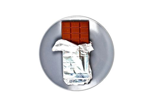 Chocolate bar with foil on grey ceramic plate isolated on white background.