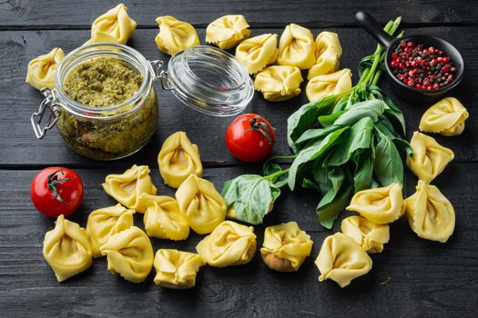 Raw Tortellini with basil and pine pesto, on black wooden table background