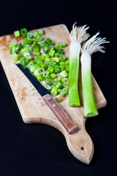 Fresh green organic chopped onions and knife on a cutting board.