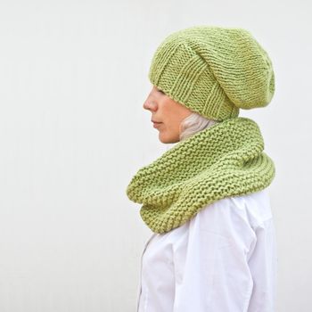 Pretty young woman in warm green knitted hat and snood. 
