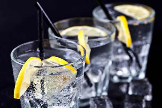 Three glasses with fresh cold carbonated water with lemon slices and ice cubes closeup.