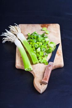 Fresh green organic chopped onions and knife on a cutting board. 