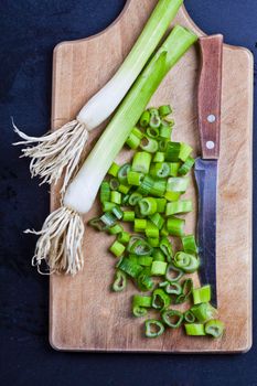 Fresh green organic chopped onions and knife on a cutting board. 