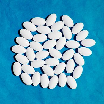 White vitamin pills group on blue background.