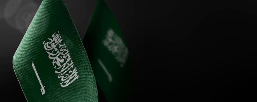 Small national flags of the Saudi Arabia on a dark background