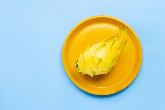 Yellow pitahaya or dragon fruit on yellow plate on blue background.