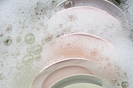 Washing dishes, Close up of utensils soaking in kitchen sink.