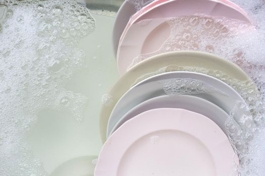 Washing dishes, Close up of utensils soaking in kitchen sink.