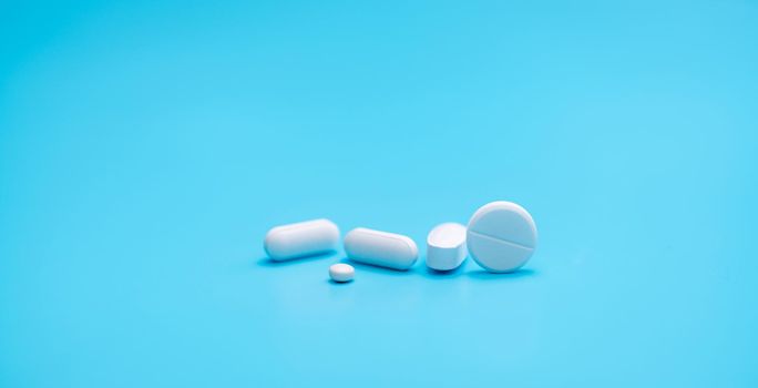 Round white tablets pills on blue background. Tablets and caplets pills pharmaceutical dosage form. Pharmacy and health topics background. Pharmaceutical industry banner. Online pharmacy store banner.