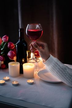 Romantic Candlelight Dinner for Two Lovers. Woman hand holding a glass of wine