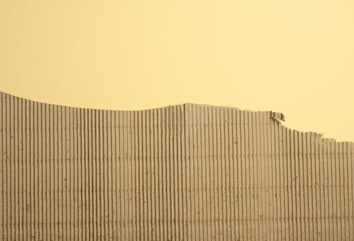 brown corrugated cardboard with torn edges on a yellow background,