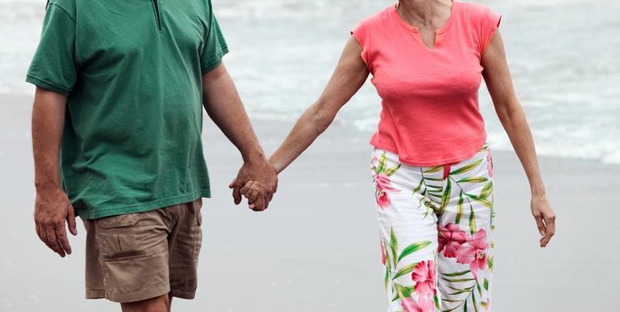 Photo of mid adult couple walking on the beach
