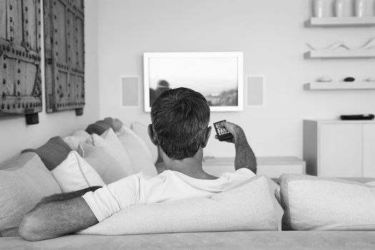 Black and white photo of man watching tv during lockdown