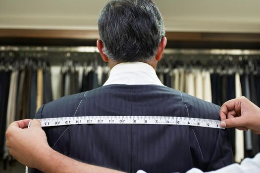 Tailor measuring business man for suit