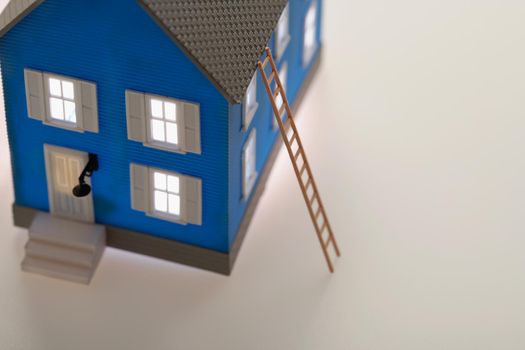 Illuminated little blue model house with ladder