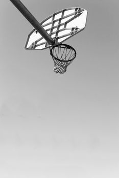 Low angled black and white photograph of a basket ball net and hoop and backboard