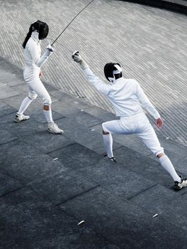 Two fencers fencing outside together