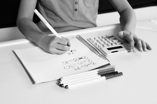 Black and white photo of Child doing maths homework using calculator