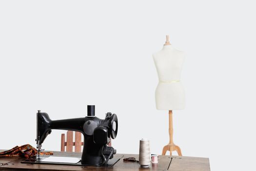 Mannequin and sewing machine with threads over gray background