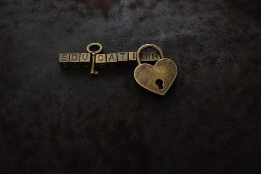 Love shaped padlock, key and education wording on dark background
