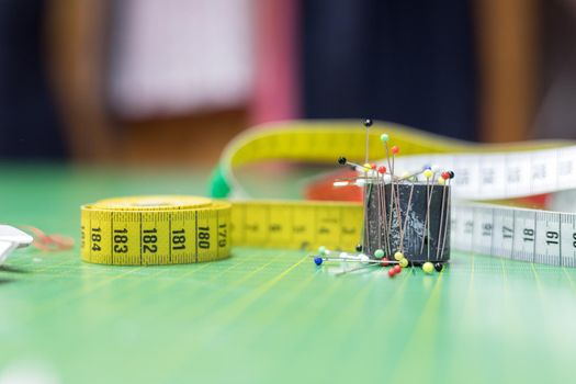 Dressmaker workshop: Close up of measuring tape, needles and thread