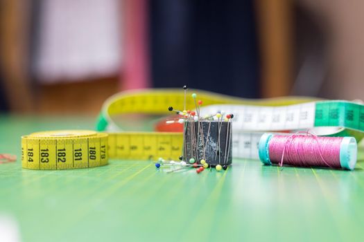 Dressmaker workshop: Close up of measuring tape, needles and thread