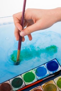 Paint dissolving as painting brush touches water 