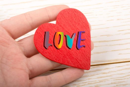 Red color heart shaped object in hand with LOVE wording