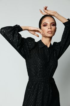 woman holding hand on head bright makeup black dress studio