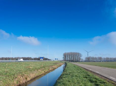 meadow and trees near motorway A27 and A2 in the netherlands under blue sky near Vianen and Utrecht