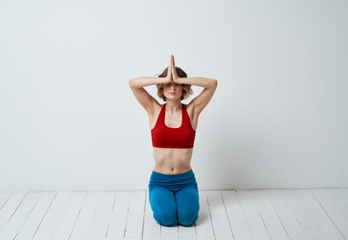 A slender woman is engaged in yoga for beginners on a light background in full growth