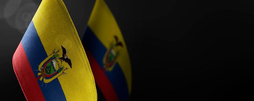 Small national flags of the Ecuador on a dark background