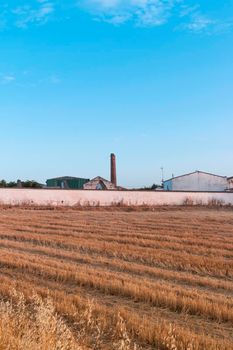 Freshly picked dry cereal field with factory in the background, in southern Andalusia Spain.