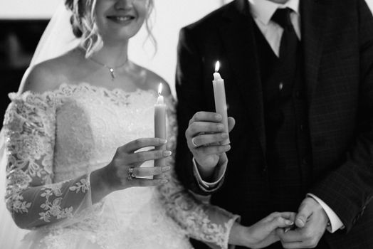 atmospheric decor of candles with live fire in the hands of the newlyweds