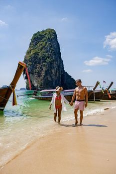 couple mid age on tropical beach in Thailand, tourist walking on a white tropical beach, Railay beach with on the background lontail boat drop off tourist