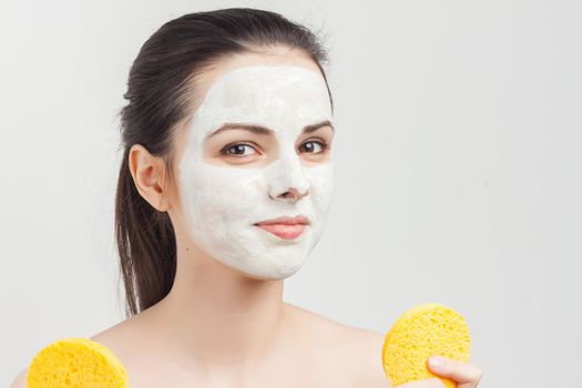 woman with bare shoulders with bum in hands removing mask from face
