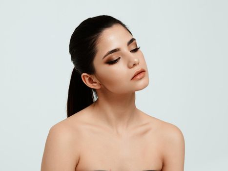 young woman with bare shoulders face makeup and closed eyes