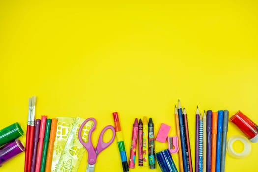 School supplies like pencil scissor eraser ruler watercolor mask alcohol sanitizer inside a brown bag backpack on yellow background. Back to school concept during covid pandemic with copy space