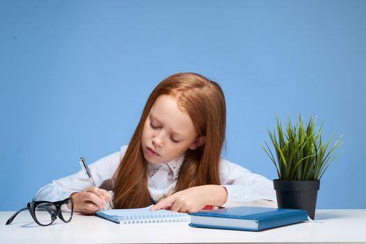 red-haired girl doing homework at the table school subject education. High quality photo