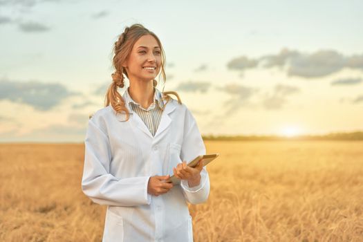 Woman farmer white coat smart farming standing farmland smiling using digital tablet Female agronomist specialist research monitoring analysis data agribusiness