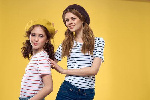 Cheerful sisters in hats striped T-shirts joy lifestyle yellow background family. High quality photo