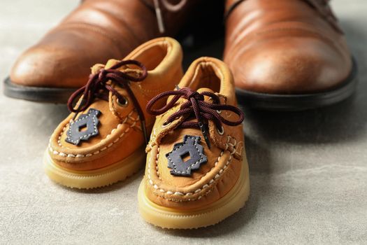 Brown leather shoes and children's shoes on grey background, space for text and closeup