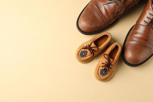 Brown leather shoes and children's shoes on color background, space for text and top view