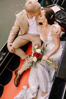 Venice, Italy - 04 october 2019: Italy wedding in Venice. A gondolier rolls a bride and groom in a classic wooden gondola along a narrow Venetian canal. Newlyweds are sitting in a boat