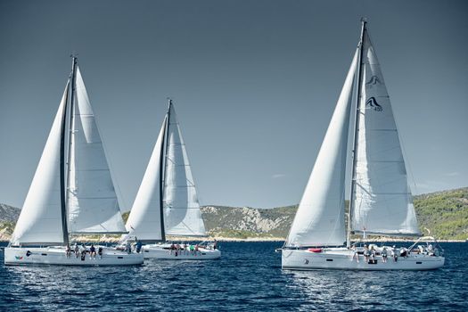 Croatia, Adriatic Sea, 18 September 2019: Sailboats compete in a sail regatta, sailboat race, reflection of sails on water, number of boat is on aft boats, island is on background, clear weather